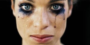 Young woman wearing black eye make-up, crying, close-up